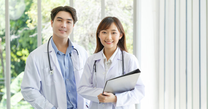 Medicine and healthcare concept : Happy and cheerful asian doctors, Male and Female holding files with stethoscope and smiling in lobby of hospital. - Powered by Adobe
