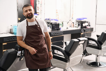 Fototapeta na wymiar Amicable young man working at neat barbershop
