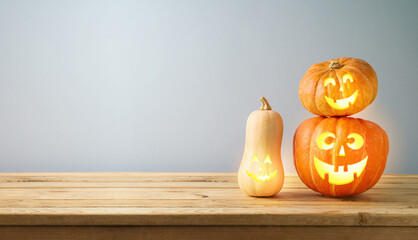 Halloween jack o lantern pumpkin decoration on wooden table over gray wall background. Holiday mock up for design and product display © maglara
