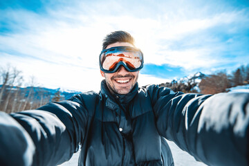 Young man taking selfie picture with smart cell phone hiking mountain on snowy slope - Happy skier...