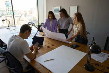 Man is using smartphone next to three colleagues in workspace