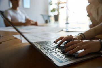 Woman hands is pressing laptop keyboard at work desk