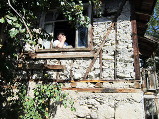 man smoking in window of old country house