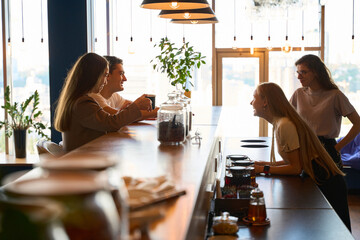 Woman is laughing next to three friends at the bar