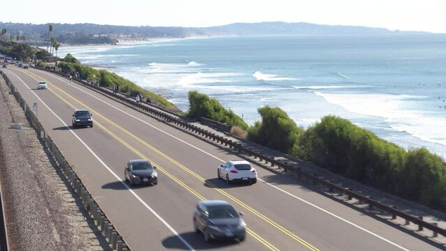 Aerial of white sports car on coastal highway 101 southern California with view of Pacific Ocean