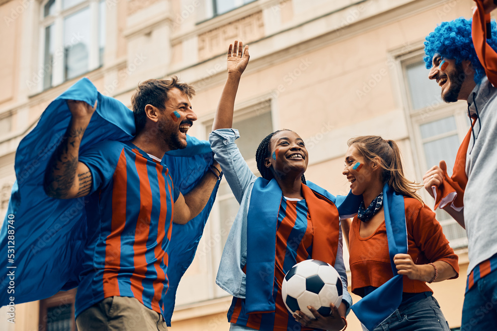 Wall mural Below view of cheerful soccer fans celebrating victory of their team.