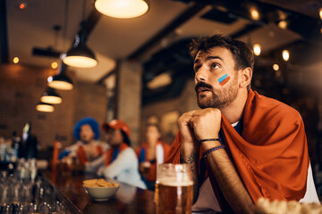 Young sports fan watching match with anticipation in bar.