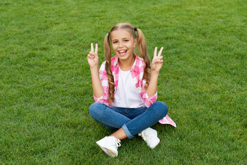 happy teen child sit on green grass outdoor. peace
