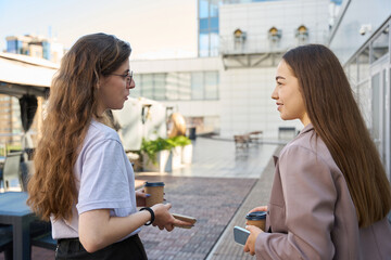 Two women talking on the street during a coffee break