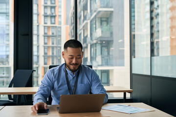 Joyous company employee using portable computer in workplace