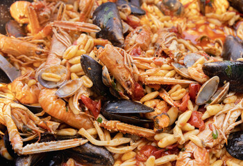 Italian Cavatelli allo scoglio, pasta with seafood and tomatoes close up in a frying pan