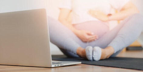 Fototapeta premium Concept banner expectant woman mother doing prenatal video training on computer with sunlight
