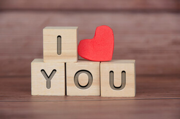 I Love You text engraved on wooden blocks with heart shape and wooden background. Romance and relationship concept