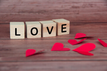 Love text on wooden blocks with heart shape and wooden background. Romance and relationship concept