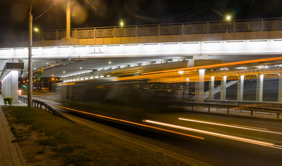 Blurred bus traffic under the overpass in the evening.