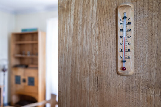 Mercury thermometer for determining the temperature indoors, hanging on a wooden wall.