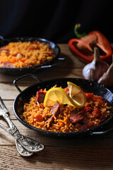 Spanish food specialty - chorizo sausage cooked with rice, tomatio, paprika, onion, garlic and saasoned with smoked paprika powder, lemon slice decoration on the top (dark and moody photography).