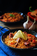 Spanish food specialty - chorizo sausage cooked with rice, tomatio, paprika, onion, garlic and saasoned with smoked paprika powder, lemon slice decoration on the top (dark and moody photography)