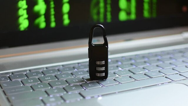 Locked padlock on top of laptop. A green digital pattern is seen on the background 