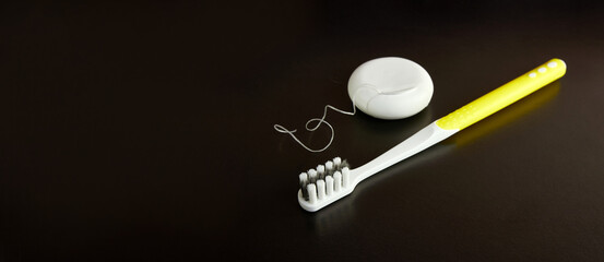 Dental floss and toothbrush on a black background. Dental care.