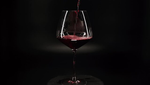 Pouring red wine into a glass on a black background 4k