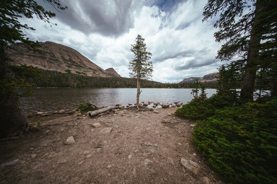 The beautiful expanse of Mirror Lake in the Uintas National Forest, surrounded by bright green trees and foliage under a cloudy, even diffuse sky