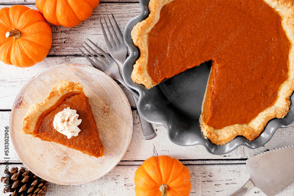 Poster slice of pumpkin pie with whipped cream topping. top view table scene on a white wood background.