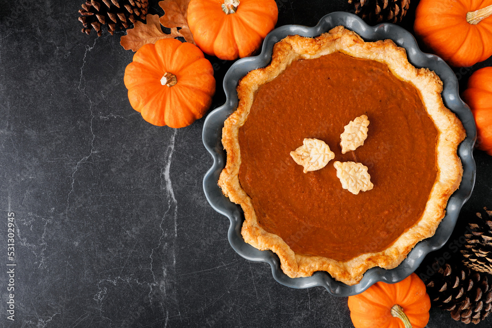 Poster Homemade fall pumpkin pie. Overhead view table scene on a dark background with copy space.