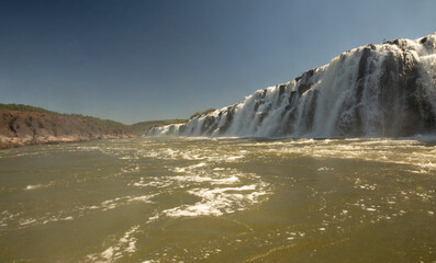Navigating the rapids. The majestic Mocona falls seen from the boat. The rocky waterfall white water, strong river current flowing across the jungle.