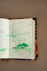 Abstract and expressive art. Top view of an artist's notebook with modern non figurative green drawings on the wooden table.