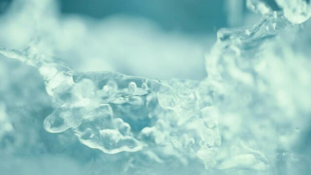 A mountain river with crystal clear water. Well water is flowing over stones. Abundant blue stream in a forest. Cold water splashing near rapids. Concept of mineral water. Super slow motion shot