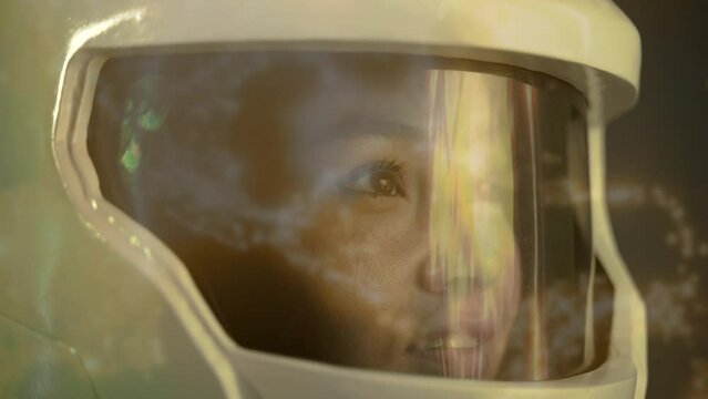 The astronaut girl watches the rotation of the digital planet. Earth from electronic data rotates around the astronaut's helmet with an orange tint