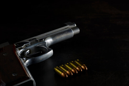 Gun. Semi automatic 9 mm parabellum stainless steel pistol on natural dark background. Low key photography.