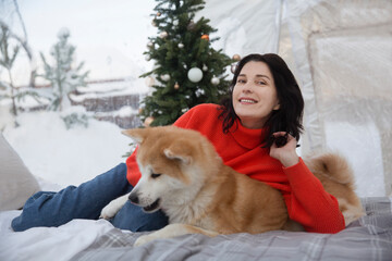 middle aged woman with a dog resting and spending time at Glamping house on winter holidays. Happy New Year concept. Christmas holiday dome tent . Cozy, camping, hygge, lifestyle concept