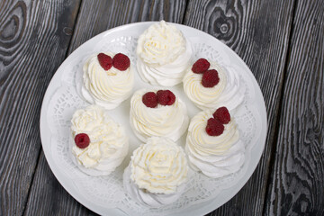 Cake Anna Pavlova, meringue and cream. Garnished with raspberries. Lying on a platter, close-up.