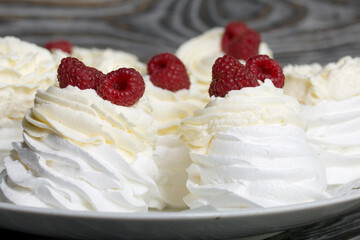 Cake Anna Pavlova, meringue and cream. Garnished with raspberries. Lying on a platter, close-up.