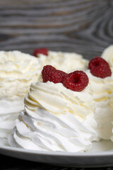 Cake Anna Pavlova, meringue and cream. Garnished with raspberries. Lying on a platter, close-up.
