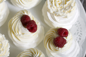 Cake Anna Pavlova, meringue and cream. Garnished with raspberries. Lying on a platter, close-up.