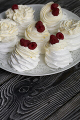 Cake Anna Pavlova, meringue and cream. Garnished with raspberries. Lying on a platter, close-up.