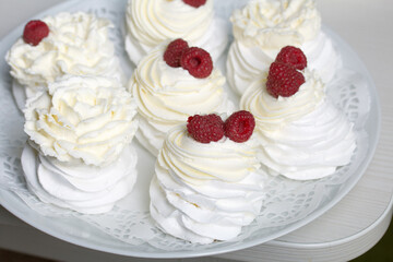 Cake Anna Pavlova, meringue and cream. Garnished with raspberries. Lying on a platter, close-up.