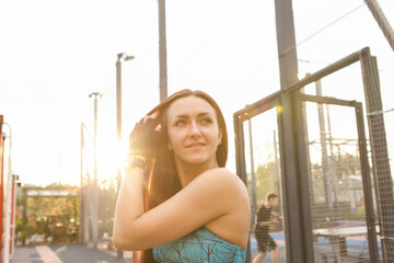 Young happy healthy fitness woman resting on street workout playground on sunset