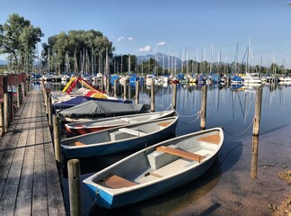 Fototapeta na wymiar Ruderboote am Steg in der Feldwieser Bucht am Chiemsee bei Übersee, Chiemgau, Bayern, Deutschland
