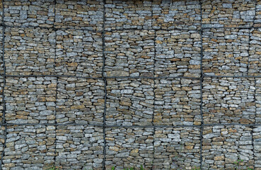 A stone wall held by a wire mesh, stone reinforcement of the highway slope