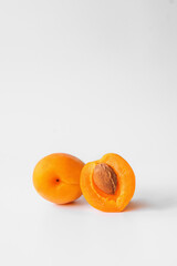 one whole apricot and half an apricot with a stone on a light background close-up