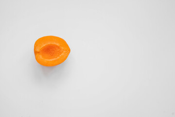 one half pitted apricot on a light background with negative space