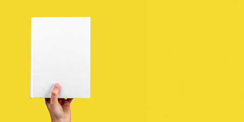 Banner with hand holding closed book mockup on yellow background. Reading hobby, study, learning new information concept. Space for text