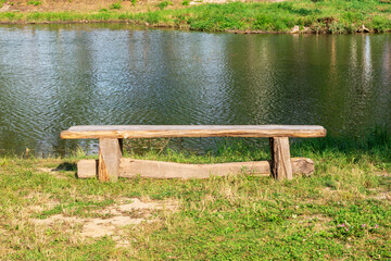 Fototapeta na wymiar A wooden bench near a pond at daytime.Beautiful view of the lake.The concept of outdoor recreation