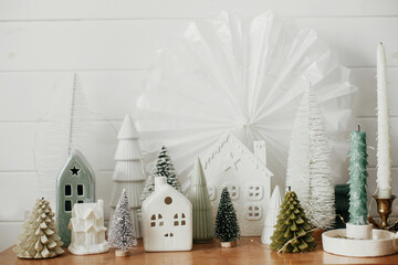 Christmas little village decoration in festive scandinavian room. Modern miniature christmas trees,...