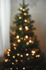 Blurry illuminated christmas tree. Abstract blurred christmas tree with golden lights in evening...