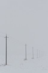 Winter fog with snow and high voltage poles